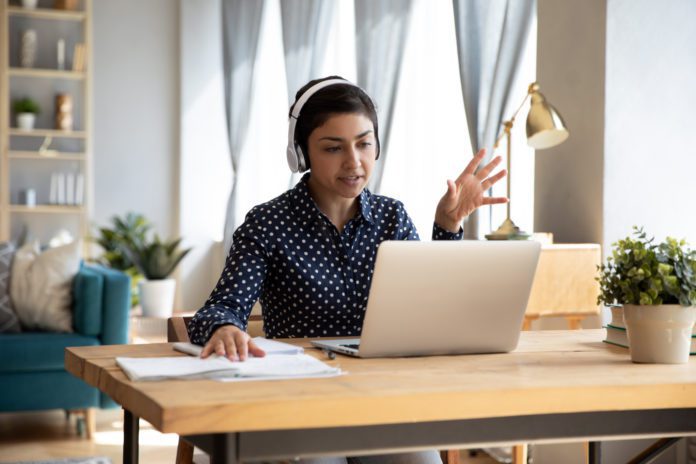 An employee works at their remote desk with a laptop and headphones.