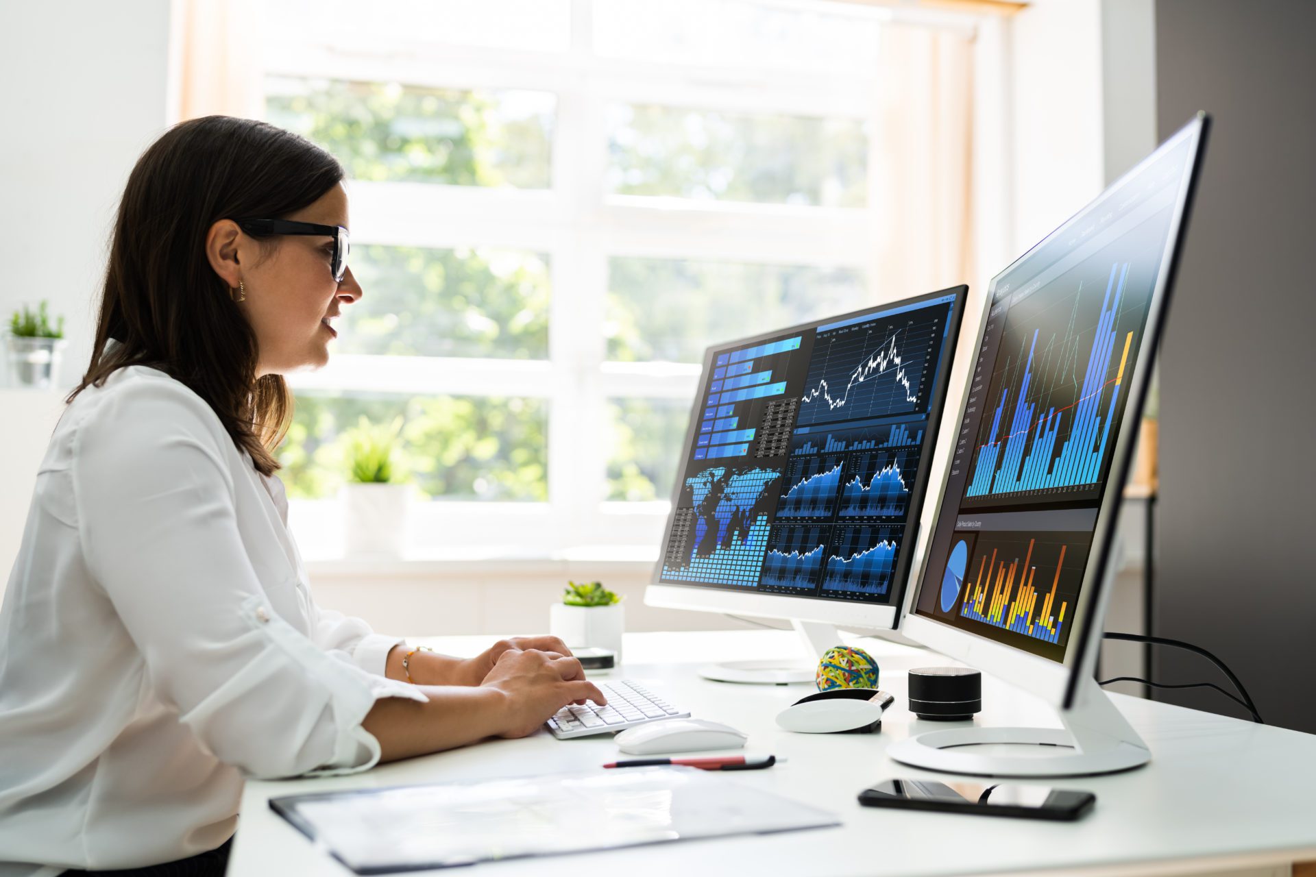 An employee reviews data analytics on a pair of monitors.